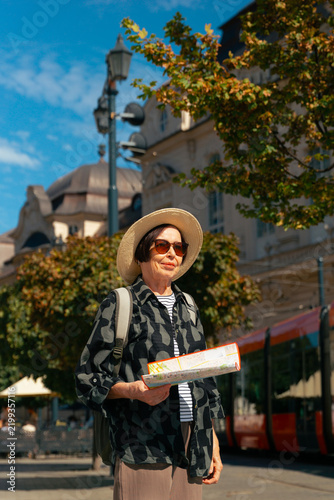 Photography elderly tourist woman holding map in sunglasses near tram in Bratislava Slovakia
