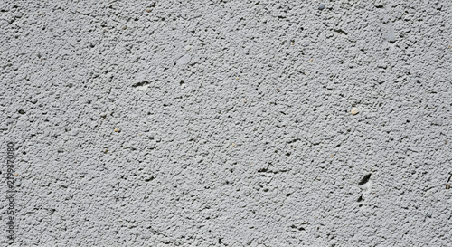 A close-up view of a rough grey concrete wall texture showing detailed porous cement surfaces perfect for architectural backgrounds and design