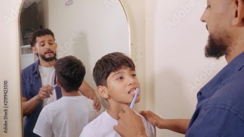 Father teaching son how to brush teeth