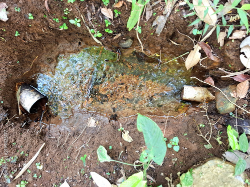 Fresh natural spring water flowing from metal pipe in rural forest irrigation.