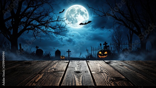 A spooky Halloween background featuring wooden planks, pumpkins, trees, and the moon against a horror-style night backdrop.