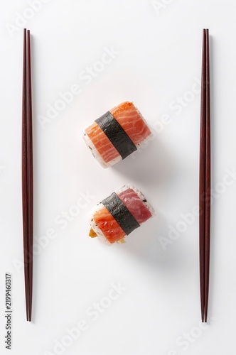 Sushi Rolls Arranged on a White Surface With Chopsticks on the Side