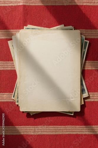 Blank Papers on a Stack of Old Photographs on a Red Textured Surface