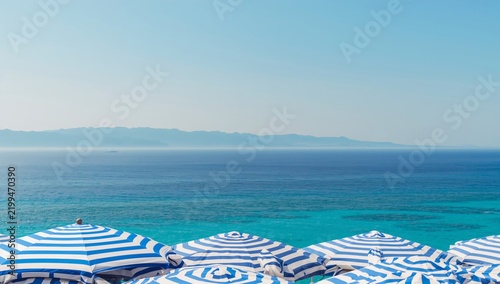 Sunny Day at the Beach With Striped Umbrellas by the Blue Sea