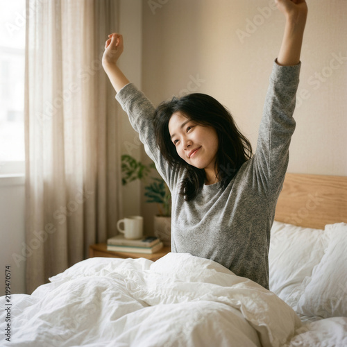 Young Woman Waking Up Stretching Arms Out In Bed