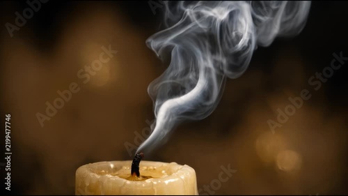 A lit candle with smoke emitting from the flame