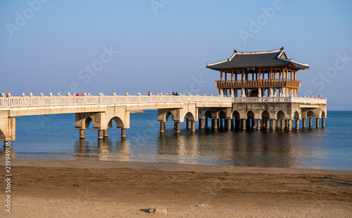 View of the Iga-ri Anchor Observatory, a traditional pavilion on a pier extending into the sea with a sandy beach in the foreground in Pohang-si, Gyeongsangbuk-do, South Korea.
