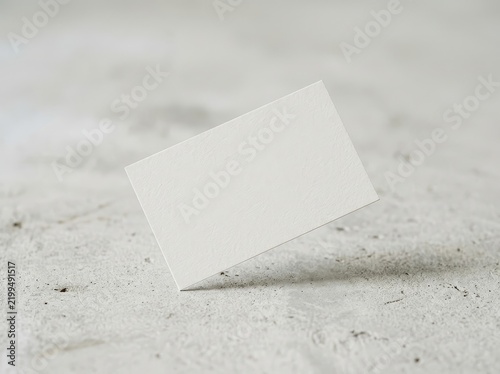 Blank white business card floating above textured surface