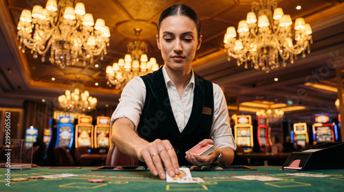Female casino dealer dealing cards at gaming table in elegant luxury casino