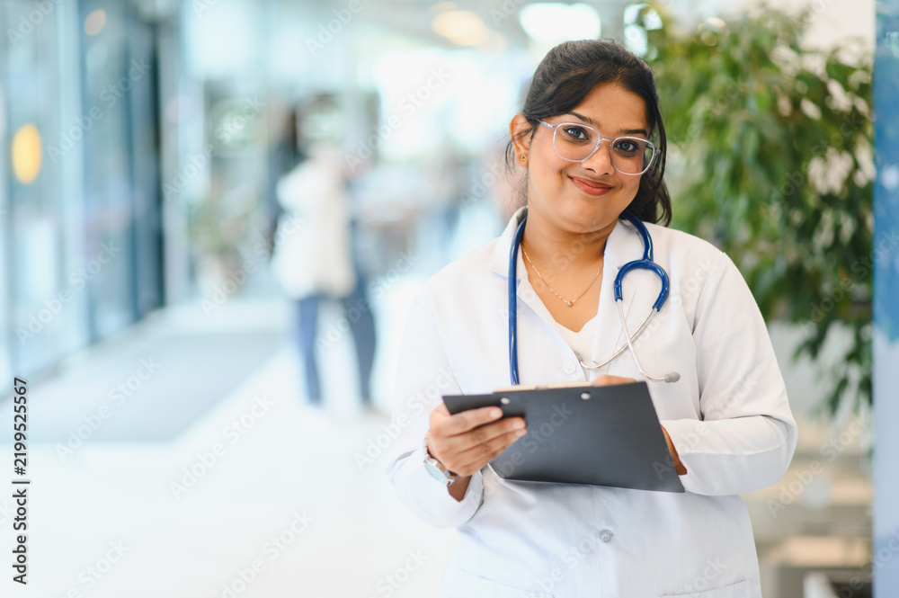 Obraz premium Indian female doctor smiling holding clipboard in hospital