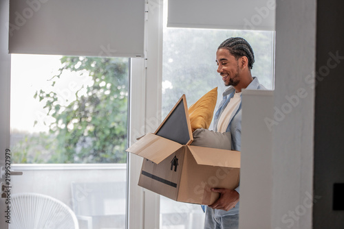 Canvastavla Young person carrying a moving box with household items into a house or office