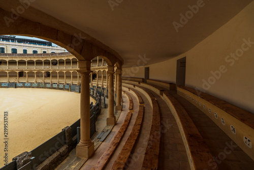 Curved wooden seating rows inside Ronda's historic bullring