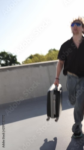 Vertical screen stressed man runs at full speed with heavy suitcases because he is late for an important meeting rushing through the city while racing against time today
