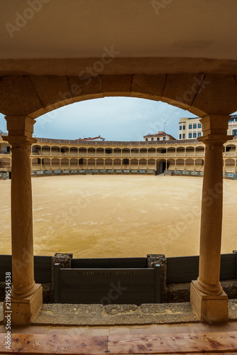 Columned view of the Ronda bullring's sandy arena and tiered stands