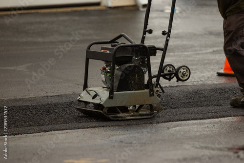 A concrete machine leveling black asphalt on a construction site. 