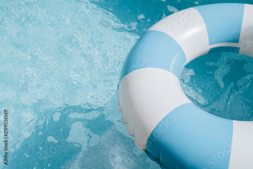 Fotografie Blue white lifebuoy floating on calm water surface conveys peaceful and safe fee