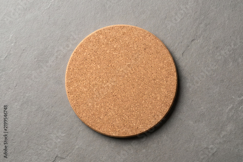 Blank round cork drink coaster top view on a grey stone background