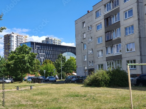 Fotografie An urban scene contrasting modern and older architecture under a bright blue sky