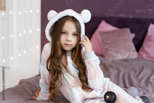 Girl in Bear Hood Pajamas Lying on Bed Holding Hood Edge