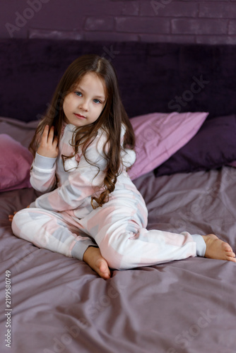 Girl in Plush Pajamas Sitting on Bed Touching Long Hair