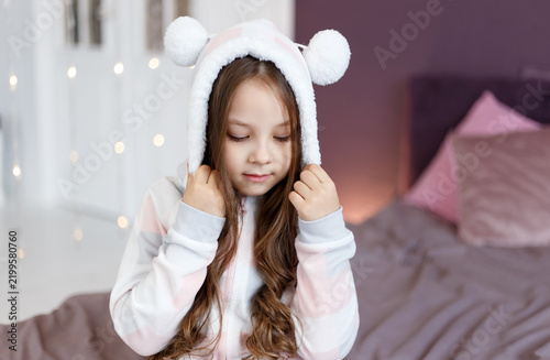 Girl in Bear Hood Pajamas Looking Down Holding Hood Strings