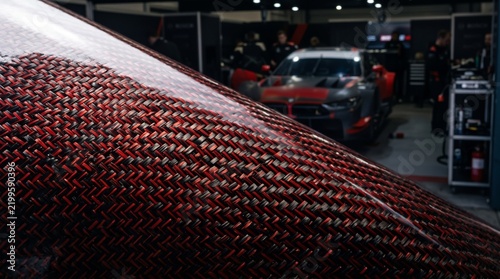 Kevlar fiber weave texture with racing cars in the background  