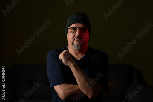 Foto Thoughtful mature man in beanie sitting in dramatic low key light