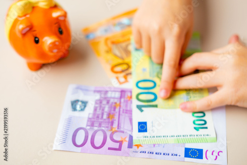 Konstfotografi Child hands counting euro banknotes table piggy bank coins, money savings allowa