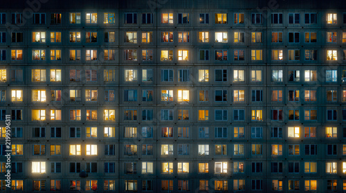 Residential building at night. Illuminated apartment windows in a high-rise housing complex show electricity consumption and urban life after dark.