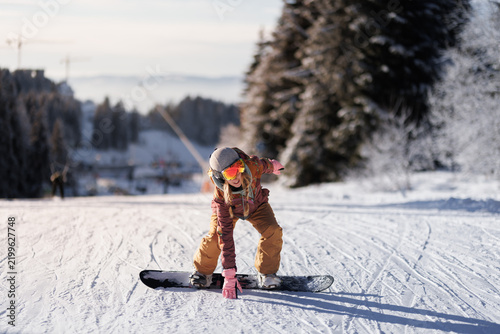 Snowboarder practices skills on a winter slope during a clear day in the mountains near a ski resort in the afternoon