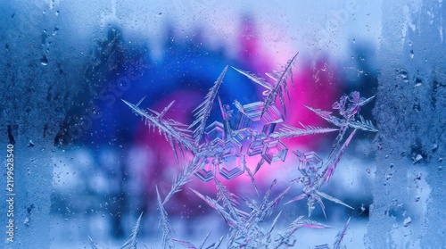 Macro frost crystals on window with colorful bokeh background.