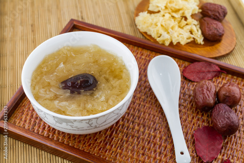 Obraz na płótnie A bowl of snow fungus soup with red dates, placed on a woven tray, accompanied by dried ingredients