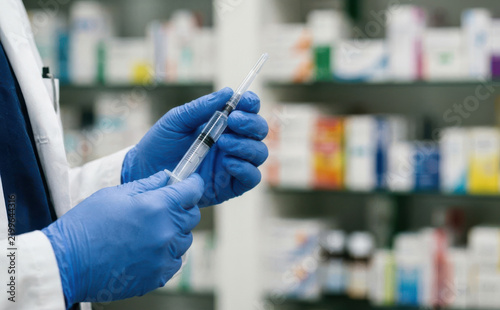 Professional doctor in blue gloves holding a medical syringe preparing a vaccine dose in a pharmacy
