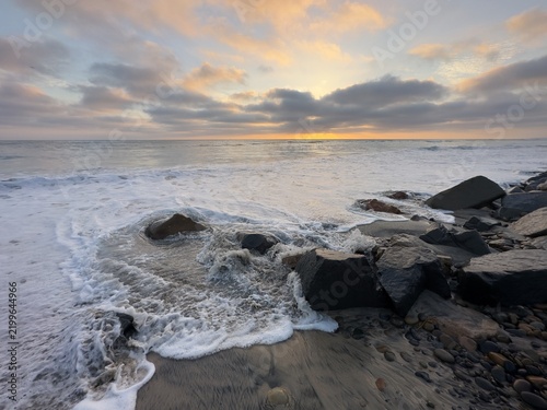 Obraz na płótnie High tide surf churning water and foam against protective riprap boulders at Ponto Beach in Carlsbad, California