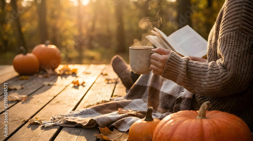 A cozy autumn afternoon featuring a woman reading a book and drinking hot coffee on a wooden terrace with pumpkins.