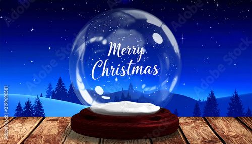 Snow globe displaying merry christmas message on wooden table