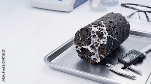 Foto Geological Core Sample of Volcanic Basalt Rock with Mineral Veins in Laboratory