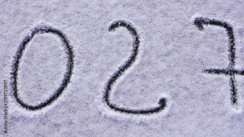 Written sketch for new year 2027. Snow background numbers ice outdoor on ground in winter. Writing text sign and drawing on field in nature frozen background. Copy space for text