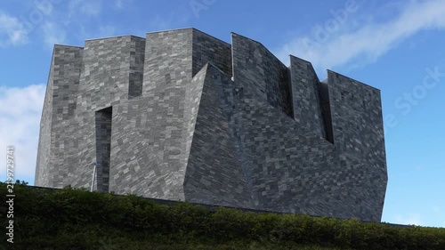 Modern art museum with grey stone facade stands under blue sky.