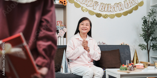 Photography Asian senior woman getting surprised with birthday gift by family at home