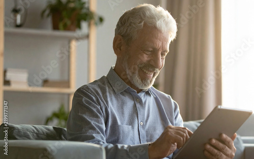 Adulto mayor utilizando una tablet para comunicarse mediante videollamada mientras recibe la cálida luz del atardecer