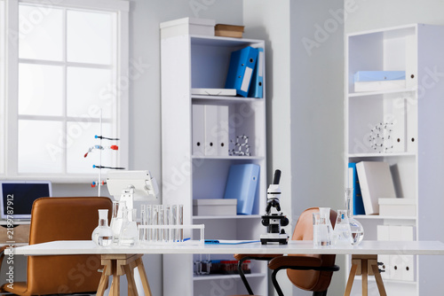 Interior of modern laboratory with microscope and different water samples in ...
