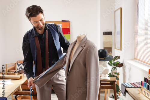 фотографія Male tailor measuring jacket on mannequin in atelier