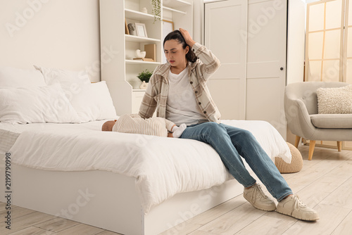 Young mother with her baby suffering from postnatal depression in bedroom