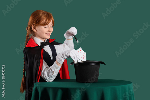 Cuadro en lienzo Young magician showing magic trick with playing cards and hat on table against g