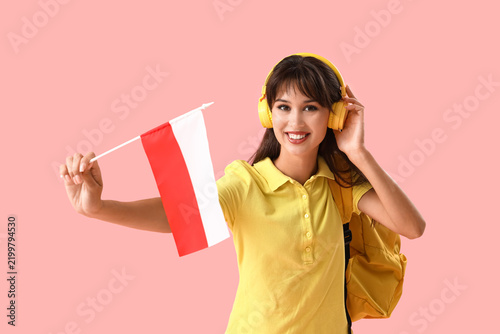 Female student in headphones with flag of Poland on pink background