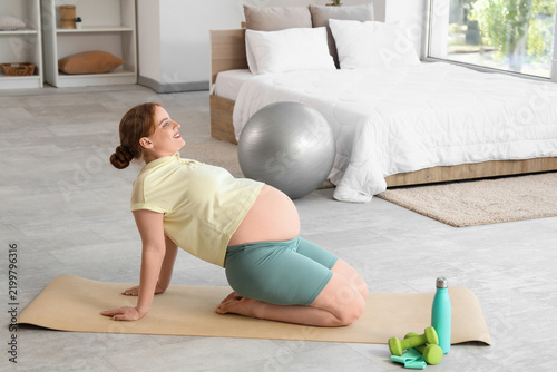 Sporty pregnant woman training in bedroom
