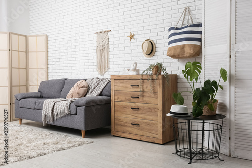 Interior of stylish living room with grey sofas, wooden dresser and summer decor