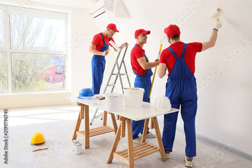 Team of male decorators painting wall in room
