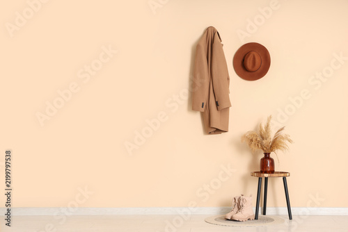 Table, vase with pampas grass and shoes near beige wall in hallway